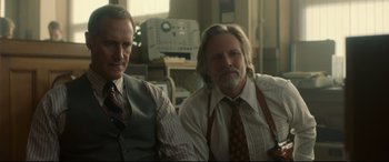 Movie still from “Stockholm” (2018), directed by Robert Budreau – Two men sitting next to each other in front of a computer; Medium shot, Low angle