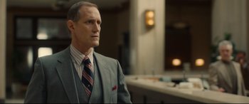 Movie still from “Stockholm” (2018), directed by Robert Budreau – A man in a suit and tie in a room; Close Up shot, Over the shoulder angle