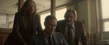 Movie still from “Stockholm” (2018), directed by Robert Budreau – A man in a suit sitting in front of two other men; Medium shot, Low angle