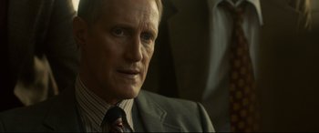 Movie still from “Stockholm” (2018), directed by Robert Budreau – A person wearing a suit and tie; Close Up shot, Over the shoulder angle