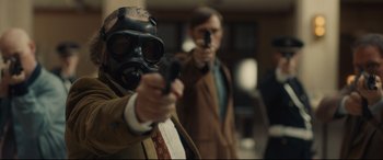 Movie still from “Stockholm” (2018), directed by Robert Budreau – A man wearing a gas mask and holding a gun; Medium shot, Over the shoulder angle