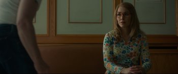 Movie still from “Stockholm” (2018), directed by Robert Budreau – A woman sitting on top of a bench in a room; Medium shot, Over the shoulder angle