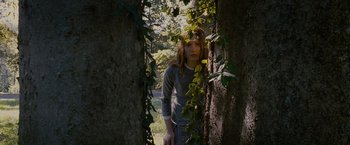 Movie still from “Stoker” (2013), directed by Park Chan-wook – A young woman standing next to a tree in the woods; Medium shot, Low angle