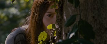 Movie still from “Stoker” (2013), directed by Park Chan-wook – A woman with long brown hair peeking out from behind a tree; Close Up shot, Low angle