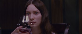 Movie still from “Stoker” (2013), directed by Park Chan-wook – A woman holding a glass of red wine in front of her face; Close Up shot, High angle