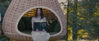 Movie still from “Stoker” (2013), directed by Park Chan-wook – A woman sitting on a chair holding a book; Medium shot, Low angle