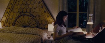 Movie still from “Stoker” (2013), directed by Park Chan-wook – A woman sitting on a bed looking at a book; Medium shot, Over the shoulder angle