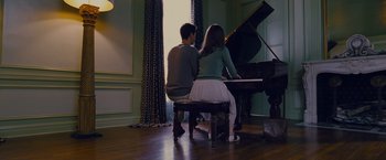 Movie still from “Stoker” (2013), directed by Park Chan-wook – A man and a woman sitting at a table playing a piano; Wide shot, High angle