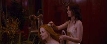 Movie still from “Stoker” (2013), directed by Park Chan-wook – A woman brushing another woman's hair in front of a mirror; Medium shot, Over the shoulder angle