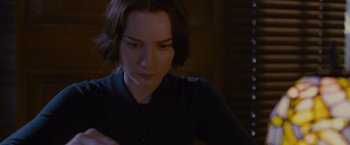 Movie still from “Stoker” (2013), directed by Park Chan-wook – A woman sitting in front of a table looking down; Close Up shot, High angle