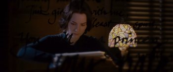 Movie still from “Stoker” (2013), directed by Park Chan-wook – A woman sitting in front of a window looking at a book; Close Up shot, High angle