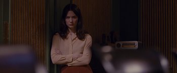 Movie still from “Stoker” (2013), directed by Park Chan-wook – A woman standing in front of a window with her arms crossed; Medium shot, Over the shoulder angle
