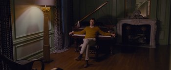 Movie still from “Stoker” (2013), directed by Park Chan-wook – A man sitting on top of a piano in a living room; Wide shot, Low angle