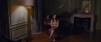 Movie still from “Stoker” (2013), directed by Park Chan-wook – A woman sitting in front of a piano in a living room; Wide shot, High angle