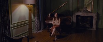 Movie still from “Stoker” (2013), directed by Park Chan-wook – A woman sitting in front of a piano in a living room; Wide shot, High angle