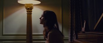 Movie still from “Stoker” (2013), directed by Park Chan-wook – A woman standing next to a lamp in a room; Medium shot, Over the shoulder angle