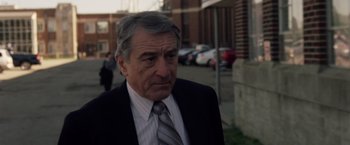 Movie still from “Stone” (2010), directed by John Curran – An older man wearing a suit and tie; Close Up shot, Over the shoulder angle