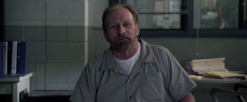 Movie still from “Stone” (2010), directed by John Curran – A man with a goatee and beard wearing a gray shirt; Close Up shot, Over the shoulder angle