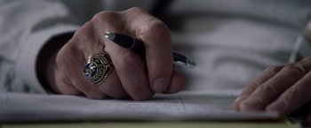 Movie still from “Stone” (2010), directed by John Curran – A person with a ring on his finger writing on a piece of paper with a fountain pen; Extreme Close Up shot, High angle