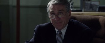 Movie still from “Stone” (2010), directed by John Curran – An older man wearing a suit and glasses; Close Up shot, Over the shoulder angle