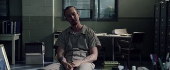 Movie still from “Stone” (2010), directed by John Curran – A man sitting on a chair in front of a window; Medium shot, Over the shoulder angle