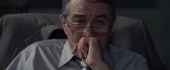 Movie still from “Stone” (2010), directed by John Curran – An older man wearing glasses and a dress shirt; Close Up shot, Over the shoulder angle