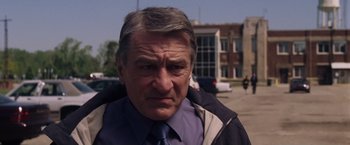 Movie still from “Stone” (2010), directed by John Curran – An older man wearing a blue tie and a black jacket; Close Up shot, Over the shoulder angle