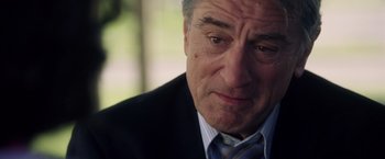 Movie still from “Stone” (2010), directed by John Curran – An older man wearing a suit and tie looking sad; Close Up shot, Over the shoulder angle