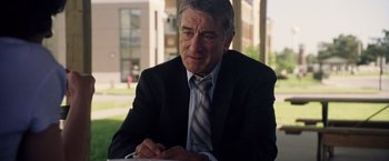 Movie still from “Stone” (2010), directed by John Curran – An older man wearing a suit and tie sitting at a table; Close Up shot, Over the shoulder angle