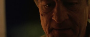 Movie still from “Stone” (2010), directed by John Curran – An older man's face is lit up by the light; Extreme Close Up shot, Low angle
