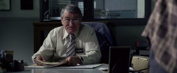 Movie still from “Stone” (2010), directed by John Curran – An older man sitting at a desk in front of a computer; Medium shot, Over the shoulder angle