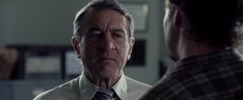 Movie still from “Stone” (2010), directed by John Curran – An older man wearing a suit and a tie; Close Up shot, Over the shoulder angle