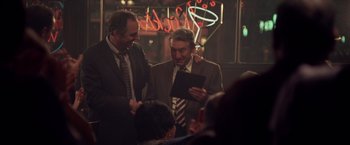 Movie still from “Stone” (2010), directed by John Curran – A couple of men standing next to each other in a room; Medium shot, Over the shoulder angle