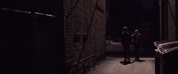 Movie still from “Stone” (2010), directed by John Curran – A person standing in a dark alleyway next to a brick wall; Wide shot, Over the shoulder angle
