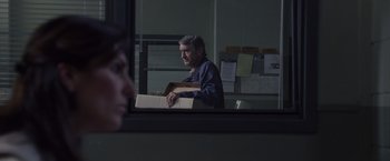 Movie still from “Stone” (2010), directed by John Curran – A man holding a box in front of a mirror; Medium shot, Over the shoulder angle