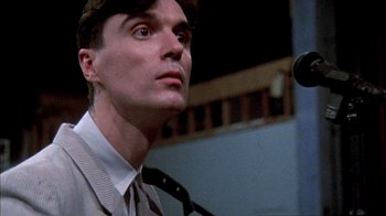 Movie still from “Stop Making Sense” (1984), directed by Jonathan Demme – A person wearing a suit and tie; Close Up shot, Low angle