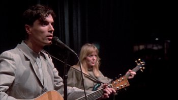 Movie still from “Stop Making Sense” (1984), directed by Jonathan Demme – A man and a woman sing into microphones; Close Up shot, Low angle