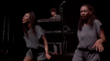 Movie still from “Stop Making Sense” (1984), directed by Jonathan Demme – A group of young people performing on a stage; Medium shot, High angle