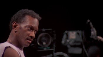 Movie still from “Stop Making Sense” (1984), directed by Jonathan Demme – A man in front of a camera in a dark room; Close Up shot, Low angle
