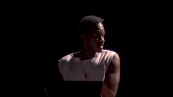 Movie still from “Stop Making Sense” (1984), directed by Jonathan Demme – A man in a white tank top is sitting in front of a computer; Close Up shot, Low angle