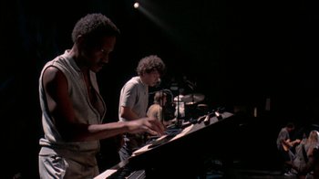 Movie still from “Stop Making Sense” (1984), directed by Jonathan Demme – Two men are playing piano in front of a microphone; Medium shot, High angle