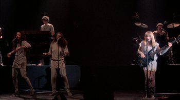 Movie still from “Stop Making Sense” (1984), directed by Jonathan Demme – A group of people on a stage singing; Wide shot, High angle