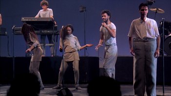 Movie still from “Stop Making Sense” (1984), directed by Jonathan Demme – A group of people on a stage singing; Wide shot, High angle