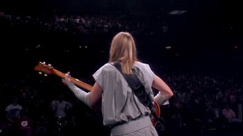 Movie still from “Stop Making Sense” (1984), directed by Jonathan Demme – A person playing a guitar in front of an audience; Medium shot, Low angle