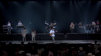 Movie still from “Stop Making Sense” (1984), directed by Jonathan Demme – A group of people on a stage playing guitar; Extreme Wide shot, High angle