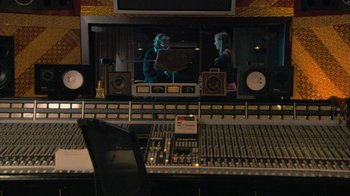Movie still from “Stories We Tell” (2012), directed by Sarah Polley – Two people are in a recording studio with a large screen; Wide shot, High angle