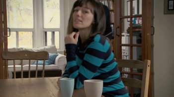 Movie still from “Stories We Tell” (2012), directed by Sarah Polley – A woman sitting at a table with two coffee cups; Medium shot, Over the shoulder angle