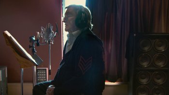 Movie still from “Stories We Tell” (2012), directed by Sarah Polley – An older man wearing headphones in a recording studio; Medium shot, Low angle