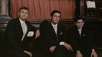 Movie still from “Stories We Tell” (2012), directed by Sarah Polley – Three young men in suits sitting next to each other; Medium shot, Low angle