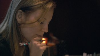 Movie still from “Stories We Tell” (2012), directed by Sarah Polley – A woman lighting a cigarette with a match in her mouth; Close Up shot, High angle